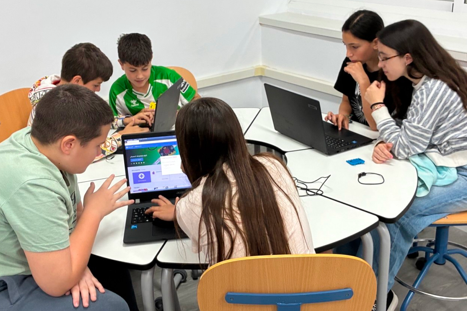Alumnado colaborando alrededor de una mesa con ordenadores portátiles en el Aula del Futuro